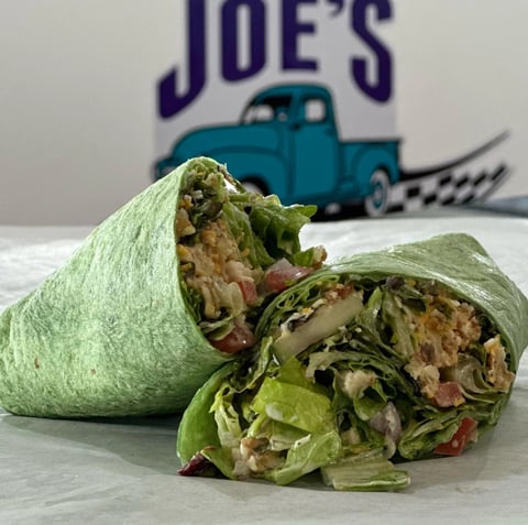 Green lettuce wraps filled with meat and vegetables in front of Joes Automotive logo with vintage blue truck